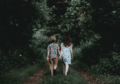 男孩和女孩手拉手走向森林
